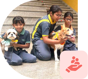 EKYA students participating in an animal care activity, holding small dogs as part of purpose-based learning initiatives at international schools in Bangalore, demonstrating practical community engagement