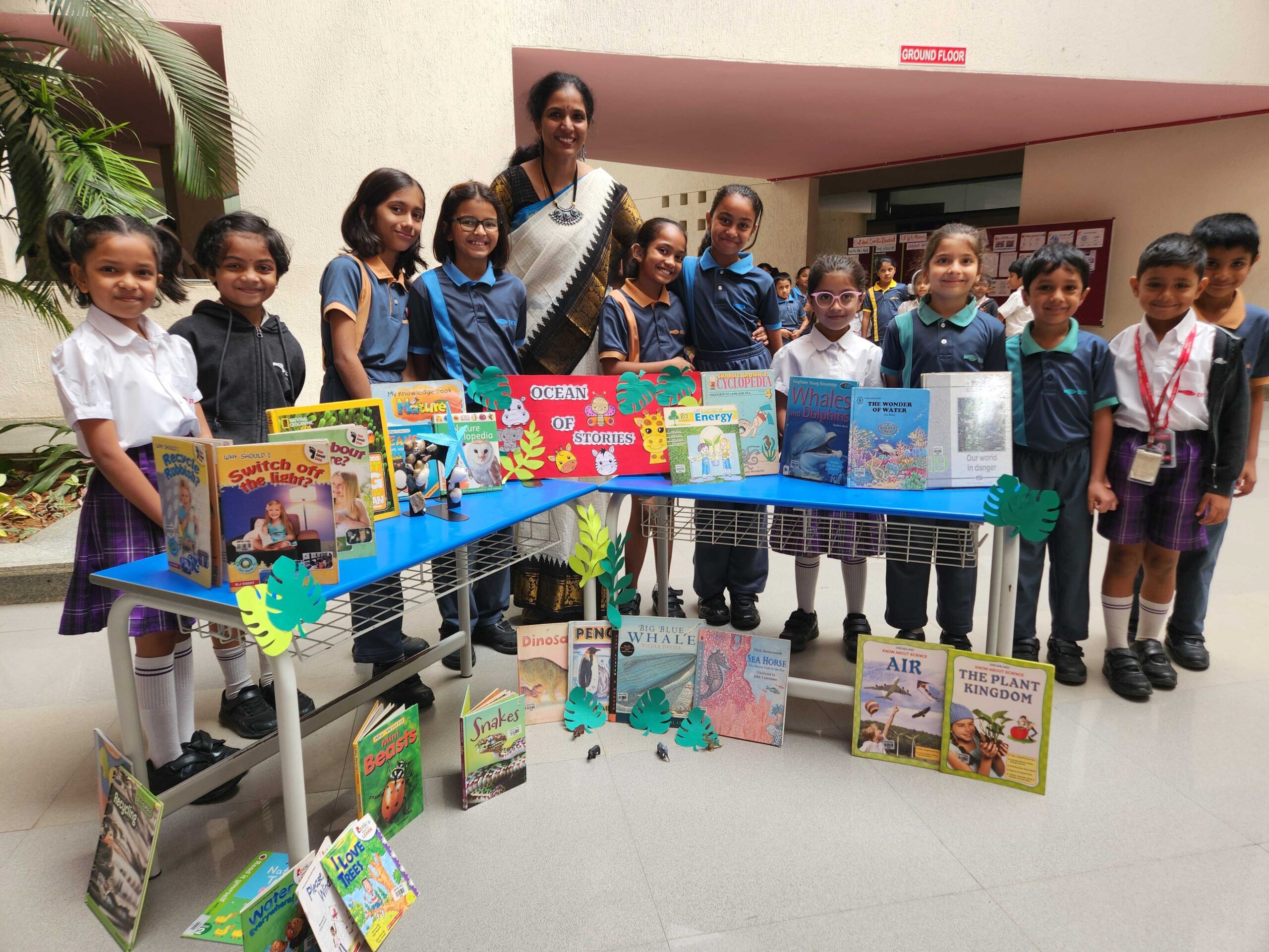 EKYA NAVA students and teacher displaying diverse collection of educational books at the 'Ocean of Stories' reading exhibition, showcasing the international school's emphasis on literacy and purpose-based learning in Bangalore